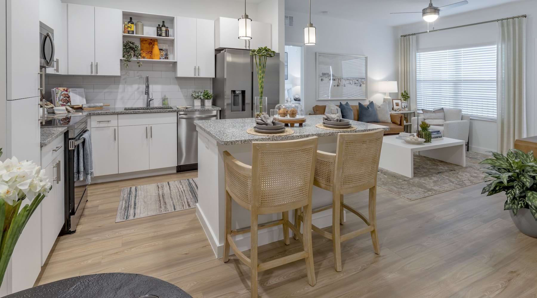 Spacious kitchen that is well lit with wood floors and stainless steel appliances with complete access to the living room 